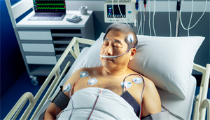 A person undergoing a sleep study with medical equipment monitoring their vital signs